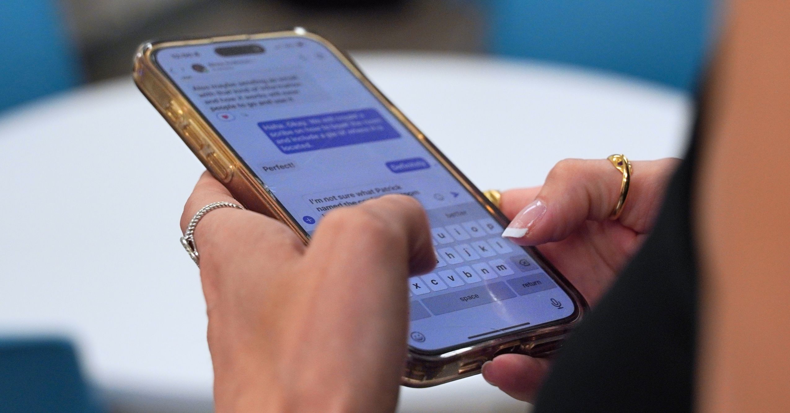 Person typing a text message on a smartphone in an office setting.