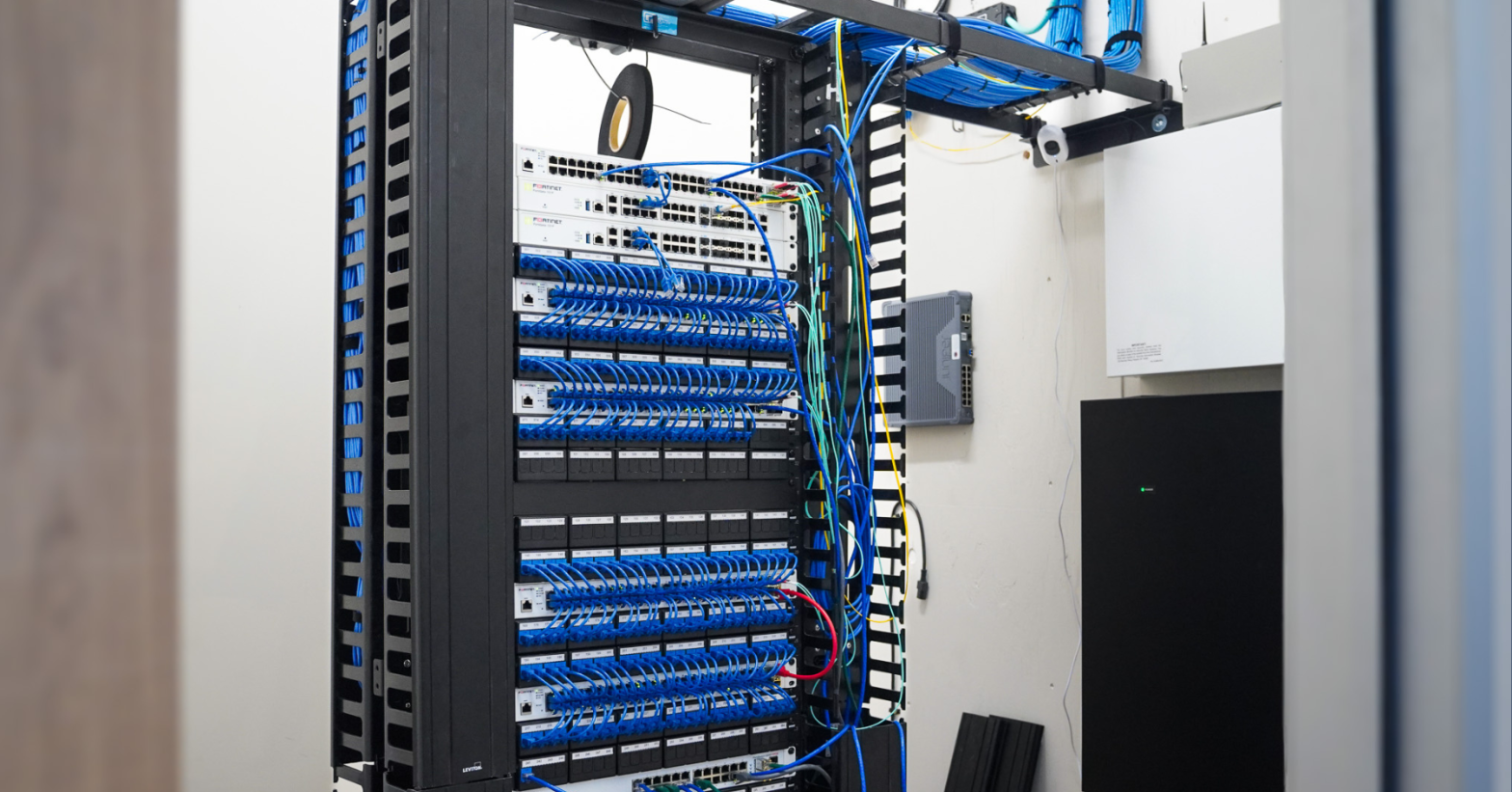 A neatly organized network server rack with blue Ethernet cables and network switches in a server room.