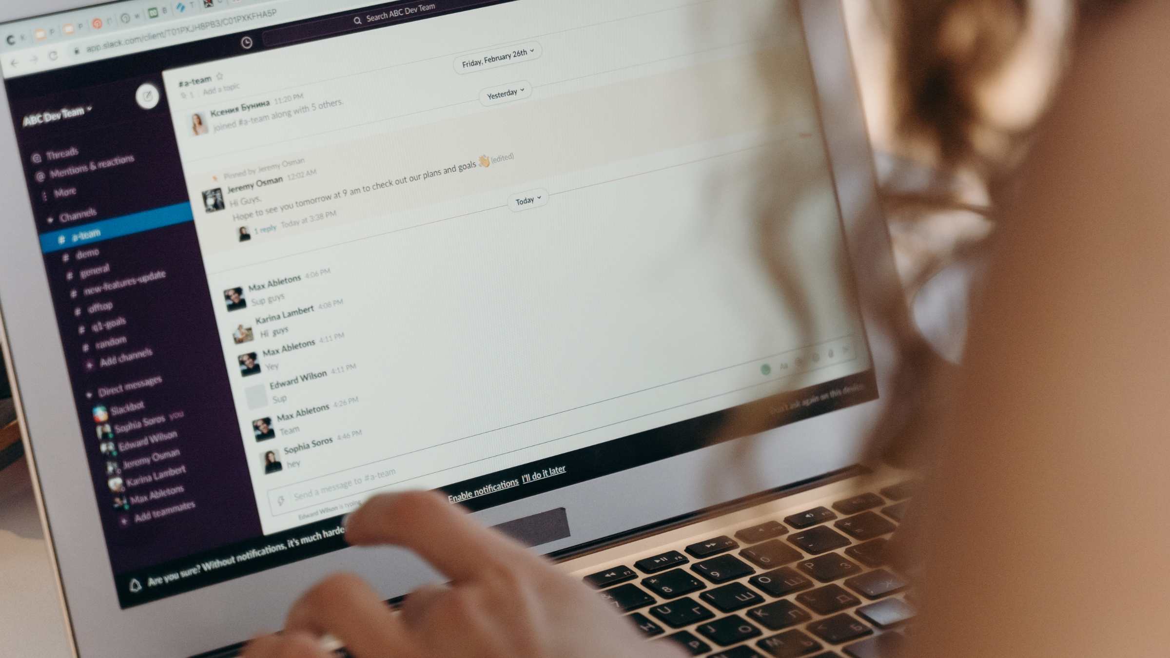 A person using a laptop with a Slack workspace open, displaying a team chat.