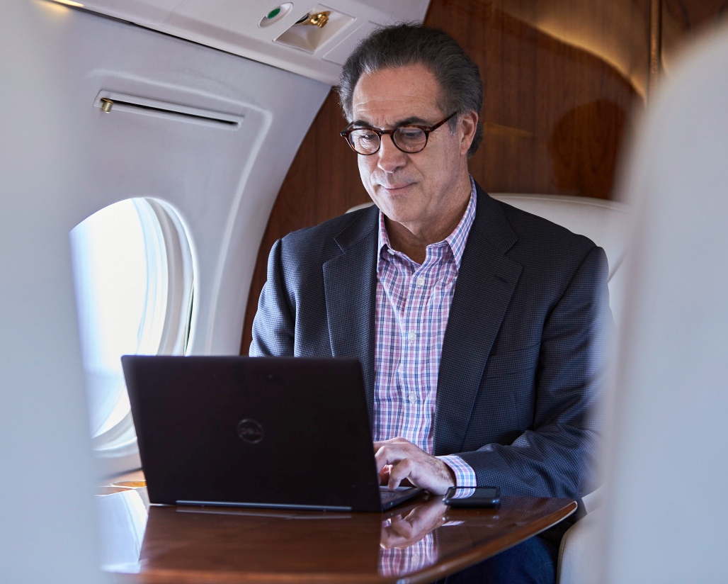 Business professional working on a laptop inside a private jet cabin.