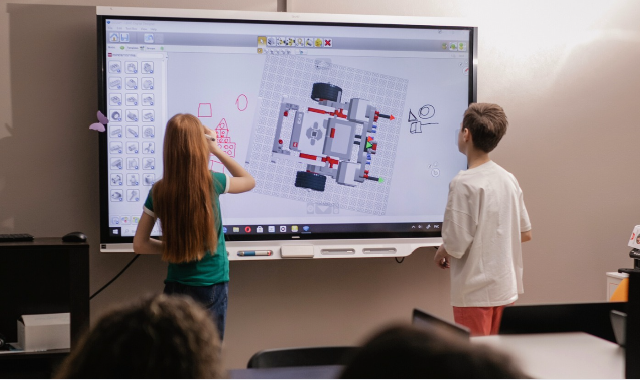 Students collaborating at an interactive smart board while designing a robotics project.