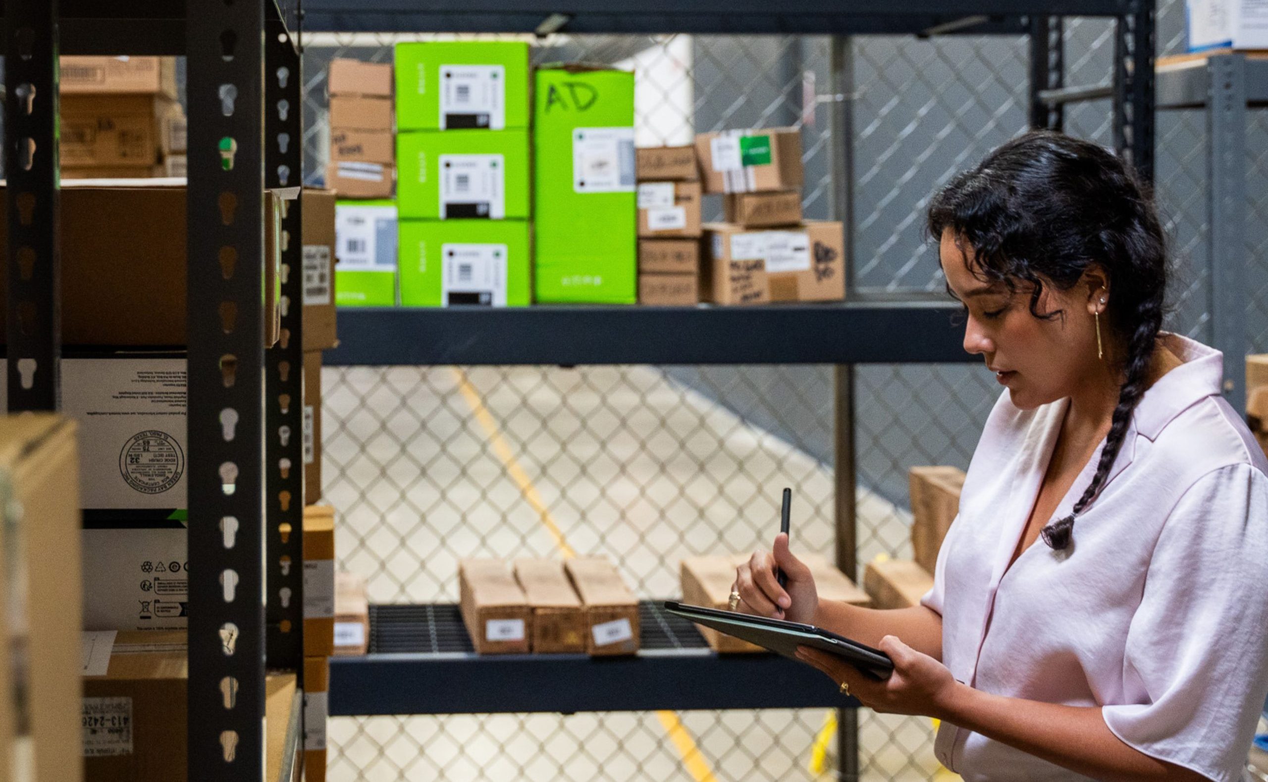Warehouse employee checking inventory and recording details on a tablet.