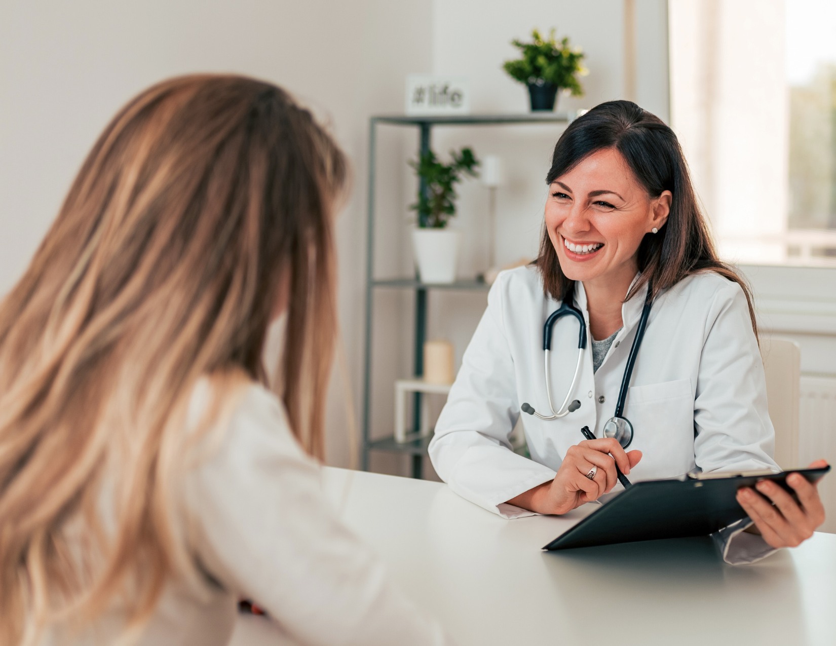 Doctor smiling while speaking with a patient during an in-office consultation.