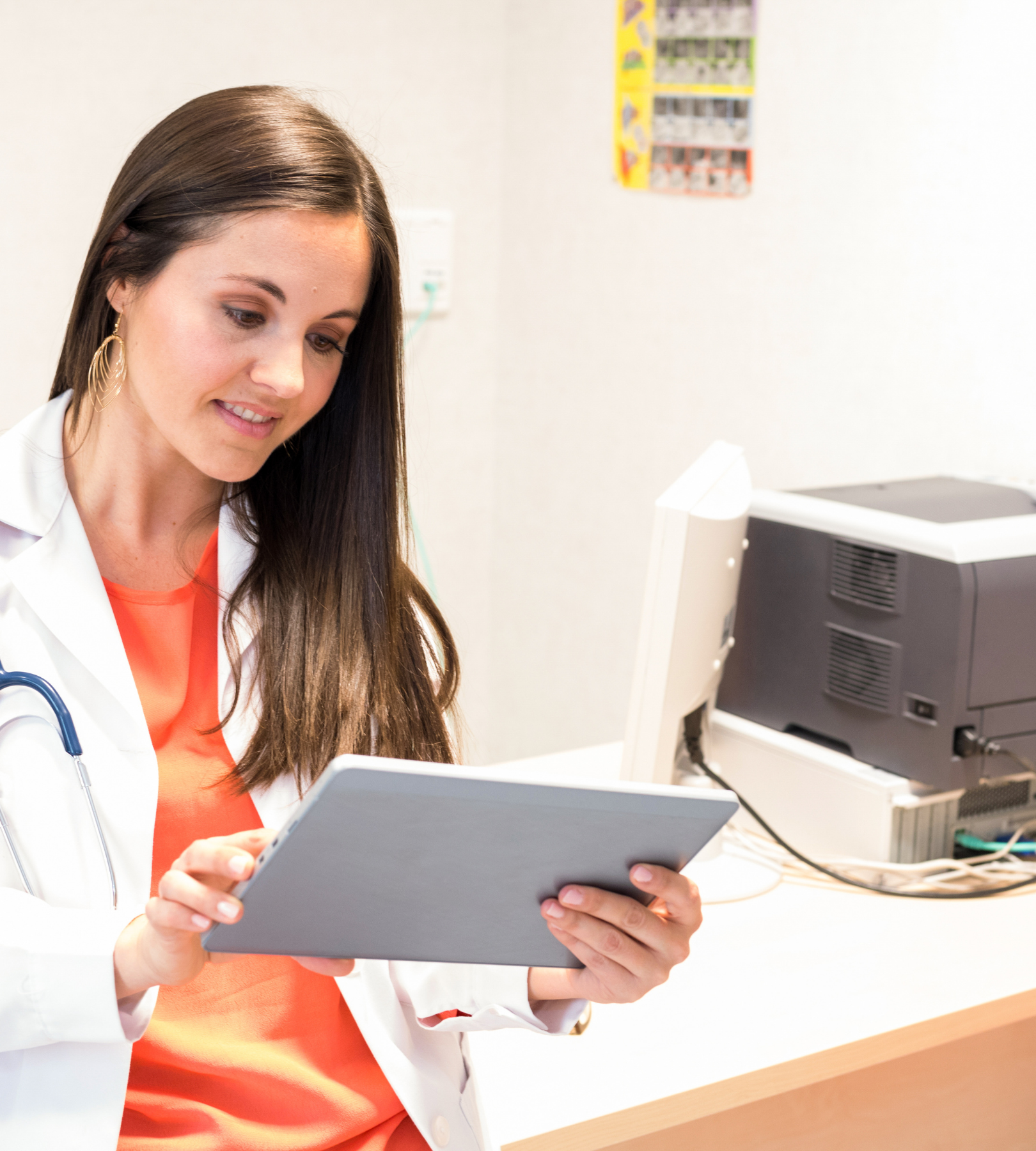 Healthcare professional reviewing patient information on a tablet in a clinical setting.